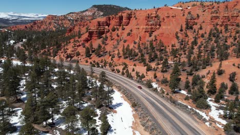 Seguimiento-De-Una-Toma-De-Drone-De-Un-SUV-Rojo-Moviéndose-Por-La-Ruta-Escénica-De-Arizona-En-Un-Día-Soleado-De-Invierno