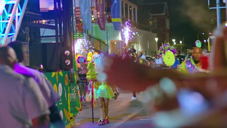Rack-focus-between-tourists-to-performers-lighting-fireworks-during-carnival-parade-at-night