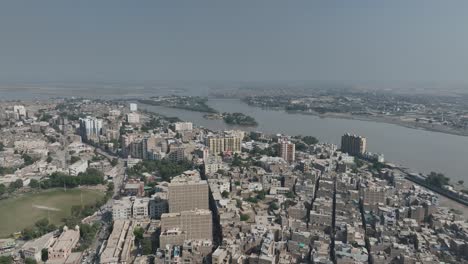 Drone-flies-over-the-city-of-Sukkur-tall-houses-and-indus-river-in-the-background