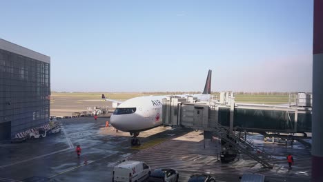 Air-Canada-airplane-at-airport-terminal-gate-with-loading-bridge-positioning-to-doors