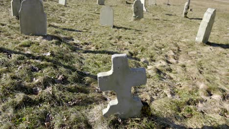 Friedhof-Mit-Vielen-Grabsteinen-Verstreut-Auf-Einer-Wiese,-Mit-Einem-Bewölkten-Himmel-Im-Hintergrund,-Lange-Schatten,-Schwenks-Nach-Oben