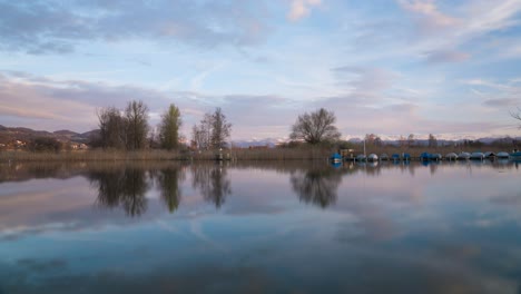 Hermosa-Puesta-De-Sol-En-Un-Lago-Con-Montañas-Al-Fondo-Y-Barcos-En-El-Lago