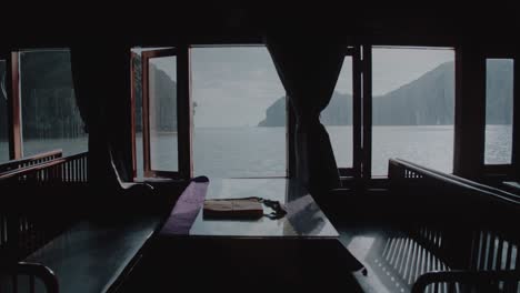 Empty-table-and-chairs-by-a-window-on-a-ferry-sailing-along-Lan-Ha-Bay-In-Vietnam