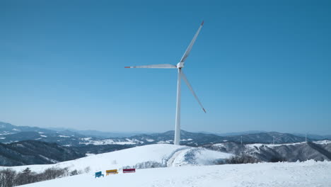 Gigantic-Wind-Turbine-Spins-Against-Clear-Sky-on-Mountain-Summit-with-Mountains-Range-in-Background-at-Daegwallyeong-Sky-Ranch,-Korea