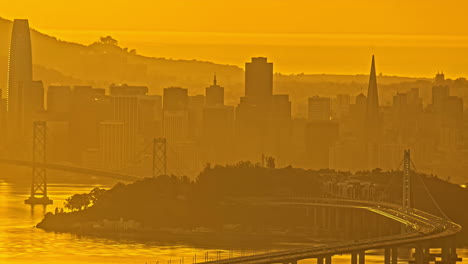Time-Lapse,-San-Francisco-Cityscape-Skyline,-Oakland-Bridge-Traffic-and-Yellow-Mist-Above-City-and-Bay