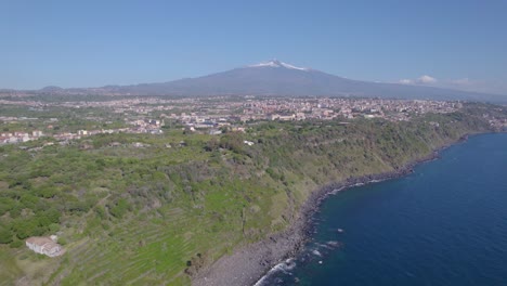 Aerial-shot-of-Mediterranean-Sea-volcanic-cliff-near-Catania,-Sicily,-Italy,-with-Mount-Etna-view