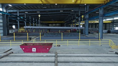 Aerial-dolly-above-empty-flatbed-semi-truck-entering-into-steel-pipe-beam-warehouse