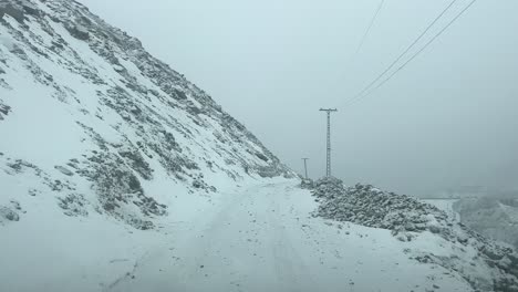 POV-Fahrt-Auf-Schneebedeckter-Straße-Am-Berghang-Durch-Die-Stadt-Skardu,-Gilgit-Baltistan,-Bei-Schlechter-Sicht