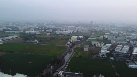 Un-Paisaje-Suburbano-Brumoso-Al-Amanecer-Con-Casas-Y-Campos,-Vista-Aérea