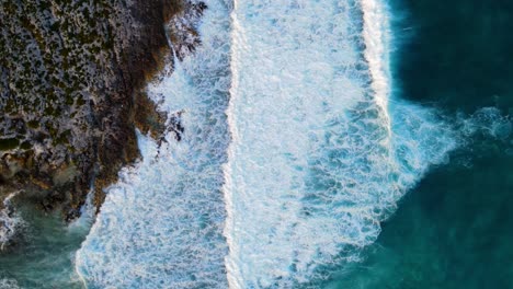 Aerial-view-of-white-spray-of-sea-waves-hitting-stones