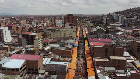 Aerial-rises-over-Oruro-Bolivia-skyline,-festive-Carnival-parade-route