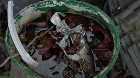 Balde-De-Tornillos-Metálicos-Oxidados-Y-Plástico-En-Agua.