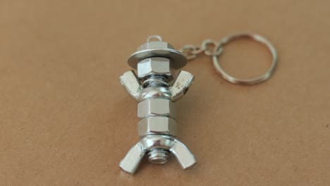 Silver-keychain-crafted-to-resemble-a-figure-with-hat,-made-from-nuts-and-bolts