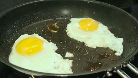 Two-sunny-side-up-eggs-sizzle,-steam-in-hot-non-stick-frying-pan
