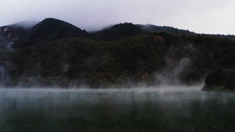 Static-aerial-shot-of-steam-rising-over-geothermal-lake-in-New-Zealand
