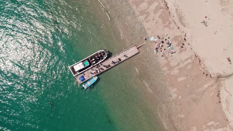 Aerial-Drone-Top-Down-fishing-boat-unloading-Wakayama-beach-Japanese-Sea,-white-sand-and-workers-and-shoppers-during-summer-day,-Japan-coastline