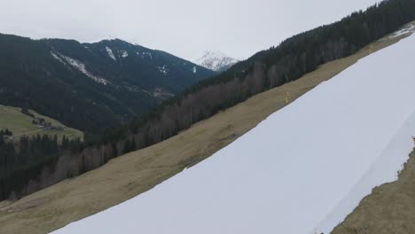 Skiers-descend-a-partially-snow-covered-slope-in-Saalbach-Hinterglemm-,-contrast-of-seasons