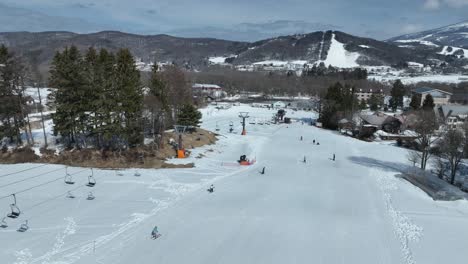 Langsame-Kamerafahrt,-Die-Den-Berg-Hinunterfliegt-Und-Dem-Sessellift-Der-Seilbahn-Folgt,-Skifahrer-Fahren-Die-Pisten-Darunter-Hinunter