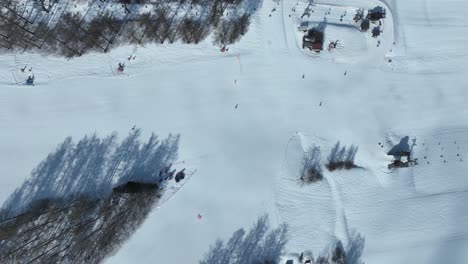 Von-Oben-Nach-Unten-Fliegender-Kameraflug-Den-Berg-Hinunter,-Dem-Skigebiet-Folgend,-Seitlicher-Flug-Aus-Großer-Perspektive