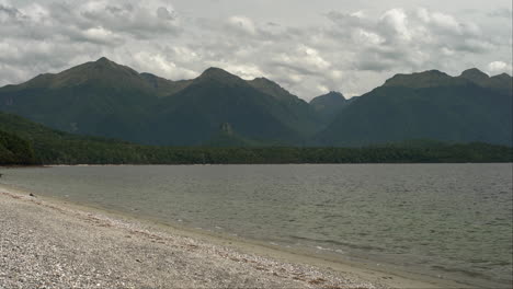 Der-Ruhige-See-Im-Fiordland-In-Neuseeland-Mit-üppigen-Bergbäumen-Im-Hintergrund-Bildet-Ein-Beeindruckendes-Panorama