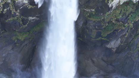 Pan-Up-of-Beautiful-Tall-Waterfall-Splashing-on-Rocks-Below