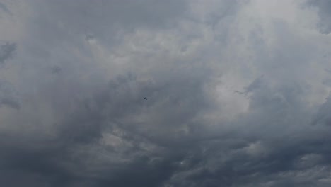 An-aeroplane-flying-under-dark-clouds,-an-overcast-sky,-weather-alert