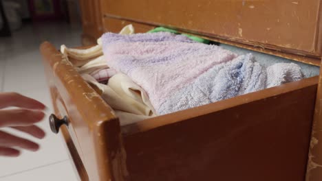 Hand-pulling-open-a-weathered-wooden-drawer-in-a-well-lit-room,-close-up