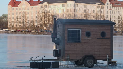 Pequeña-Y-Encantadora-Sauna-Móvil-Con-Fuego-De-Leña-En-Una-Pista-De-Patinaje-Sobre-Hielo-Al-Aire-Libre