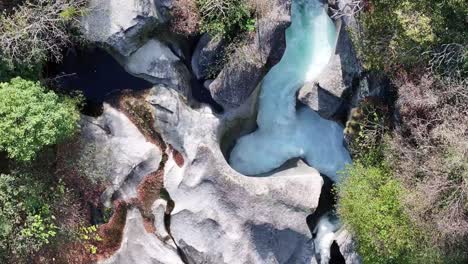 Turquoise-river-snaking-through-Foroglio's-rocky-terrain,-Maggiatal,-Tessin,-Switzerland---aerial-top-view