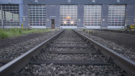 Twilight-at-a-rail-depot,-tracks-leading-into-a-train-maintenance-building