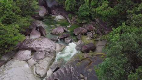 A-slow-motion-aerial-viewpoint,-the-Babinda-Boulders-in-Cairns,-Australia-reveal-fast-flowing-streams-and-dense-forests,-intertwined-massive-granite-formations,-illuminating-the-serene-name-it-bears