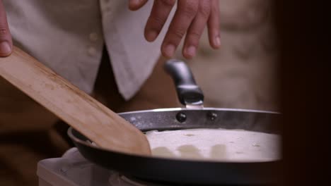 Flipping-Crepe-In-Pan-Using-Wooden-Spatula