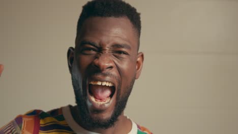 Portrait-Of-African-American-Man-Wearing-Kente-Fabric-Shirt-Excitingly-Celebrating-In-Slow-Motion