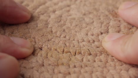 Close-up-of-hands-gently-touching-a-brown-cotton-surface,-highlighting-texture-and-detail