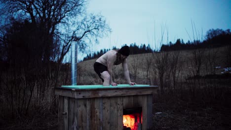 Man-Bathing-On-DIY-Wood-Burning-Hot-Tub-In-Nature-Landscape