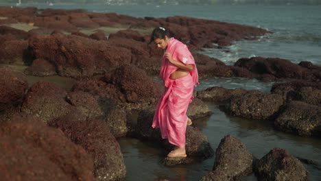 Junges-Mädchen-Im-Rosa-Kleid-Erkundet-Felsige-Küste,-Wellen-Brechen-In-Der-Nähe,-Abenteuer-Bei-Tageslicht