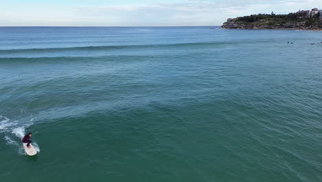 Aerial-drone-shot-following-a-female-long-board-surfer-at-Bondi-beach-in-Sydney