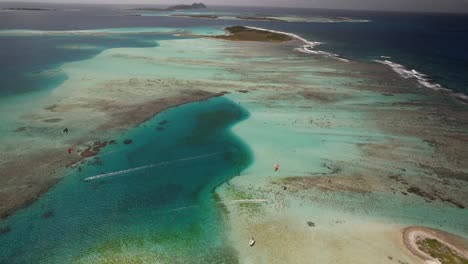 Kitesurfistas-En-Cayo-Vapor-En-Los-Roques,-Vibrantes-Tonos-Marinos,-Vista-Aérea