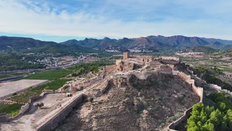 Vuelo-Cinematográfico-Con-Un-Dro-En-La-Parte-Más-Alta-Del-Castillo-De-Sagunto-Viendo-A-La-Gente-Visitarlo-Y-Con-Un-Bonito-Fondo-De-Montañas-Y-Un-Cielo-Azul-Y-Nubes-Blancas-Filmado-En-70mm-En-España.