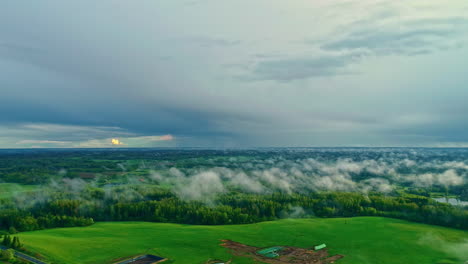 Drone-shot-of-a-stunning-wooded-field-with-low-clouds-and-a-cloudy-sky