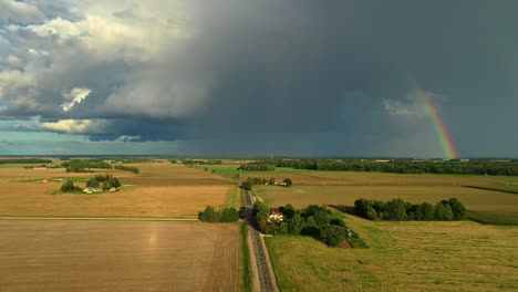 Luftaufnahme-Eines-Wolkenbruchs-In-Der-Landschaft-Lettlands,-Landwirtschaftliche-Wiese-In-Sonnenschein-Gehüllt