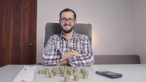 Succesful-businessman-doing-accounting-and-counting-coins-makes-a-satisfied-face-looking-to-camera