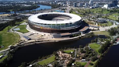 Aerial-drone-shot-flying-over-Optus-Stadium-AFL-Football-Stadium-in-Perth,-Western-Australia-by-the-Swan-River