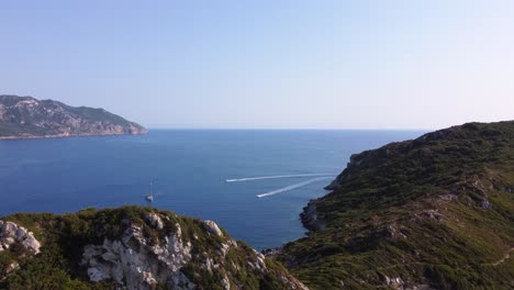 Aerial-Revealing-Coast-of-Corfu-Island-with-Tourists-Boats-passing-by,-Greece