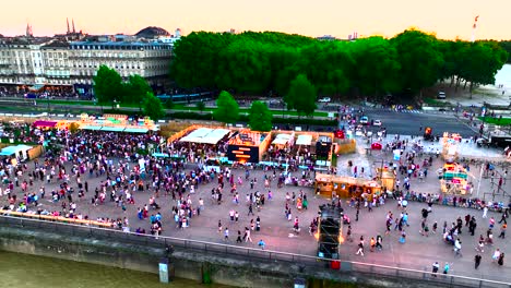 Crowds-in-Place-des-Quinconces-attending-wine-fair-with-Ferris-wheel-right,-Aerial-pan-right-shot