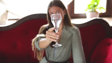 Young-attractive-Caucasian-female-model-lifting-a-glass-of-champagne,-giving-a-toast-and-drinking-it