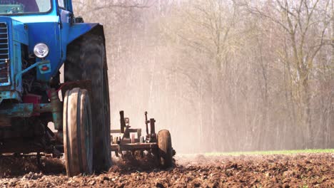 Farmer-drive-old-soviet-tractor-and-cultivate-dusty-agricultural-field