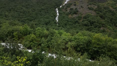 waterfall-in-a-green-forest-with-many-clouds,-norway,-nature,-drone