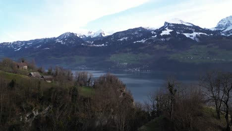 Flotando-Sobre-El-Entorno-Natural-De-Seerenbachfälle-En-Weesen-Amden,-Suiza,-Un-Sereno-Lago-Se-Encuentra-En-El-Fondo-Del-Valle,-Rodeado-Por-Montañas-Cubiertas-De-Nieve-Como-Telón-De-Fondo