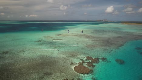 Kitesurfer-Gleiten-über-Türkisfarbenes-Wasser-Und-Korallenriffe,-Luftaufnahme,-Los-Roques